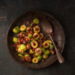 Photo of pan fried Brussel sprouts with chestnuts and bacon in a dark and moody setting
