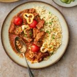 photo of beef marhpörkölt served with tarhonya in a rustic setting