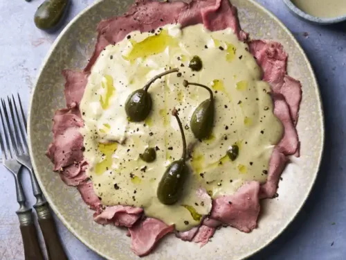 image of Vitello Tonnato, a veal dish with tuna and caper sauce from the Piedmont region in Northern Italy, served in a rustic setting