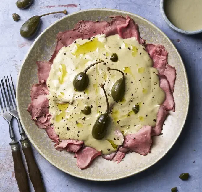 image of Vitello Tonnato, a veal dish with tuna and caper sauce from the Piedmont region in Northern Italy, served in a rustic setting