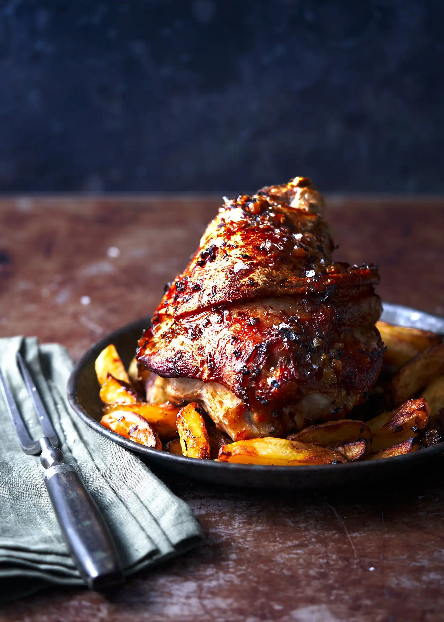 an image of the Friuli dish Stinco di Maiale served with roast potato wedges in a rustic setting