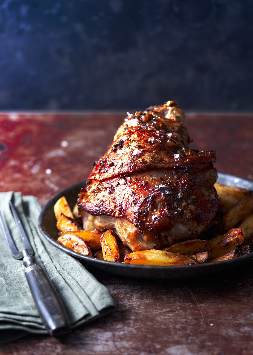 an image of the Friuli dish Stinco di Maiale served with roast potato wedges in a rustic setting