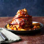 an image of the Friuli dish Stinco di Maiale served with roast potato wedges in a rustic setting