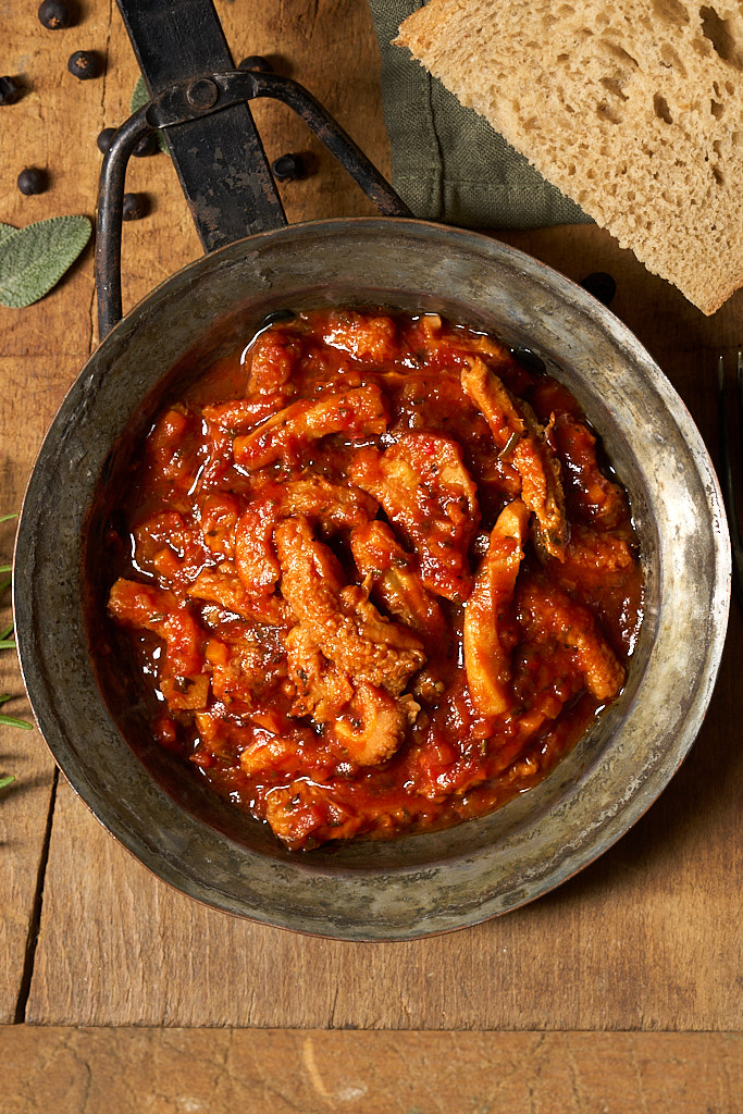 image of trippa alla Napoletana in an rustic metal pan on a wooden board