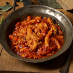 image of trippa alla Napoletana in an rustic metal pan on a wooden board