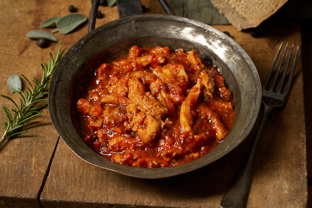 image of trippa alla Napoletana in an rustic metal pan on a wooden board