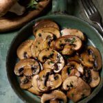rustic image of funghi alla Genovese, a classic Ligurian sautéed mushroom dish made with butter, olive oil, garlic and fresh oregano.