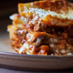 image of vincisgrassi, a rustic lasagne from Italy's Marche region, shot from side on showing all the layers of the lasagne