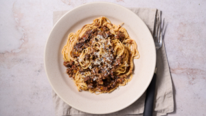image of ragu alla marchigiana, a Marche region meat sauce served in an off white bowl with Maccheroncini di Campofilone