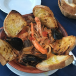 image of ciambotto - a fish soup with a variety of whole round fish, shellfish and crustaceans, served in a terracotta bowl with toasted bread