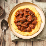 image of Goulasch alla triestina a Trieste beef stew served in a wide bowl with polenta on a wooden background