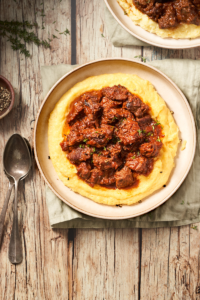 image of Goulasch alla triestina a Trieste beef stew served in a wide bowl with polenta on a wooden background