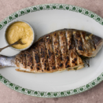 image of Orate all'Anconetana, Ancona style sea bream from the Marche region, served simply on a white oval dish with a pot of egg and bread sauce
